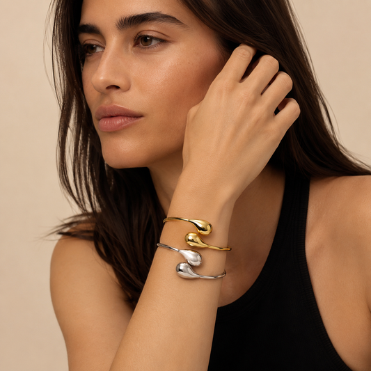Woman wearing gold and silver bracelets on a beige background