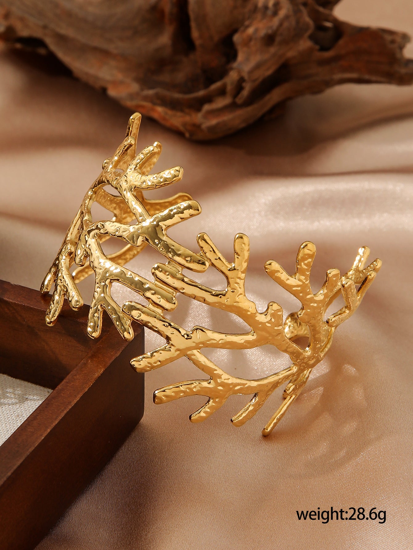 Gold leaf-shaped hair clip on a beige fabric background