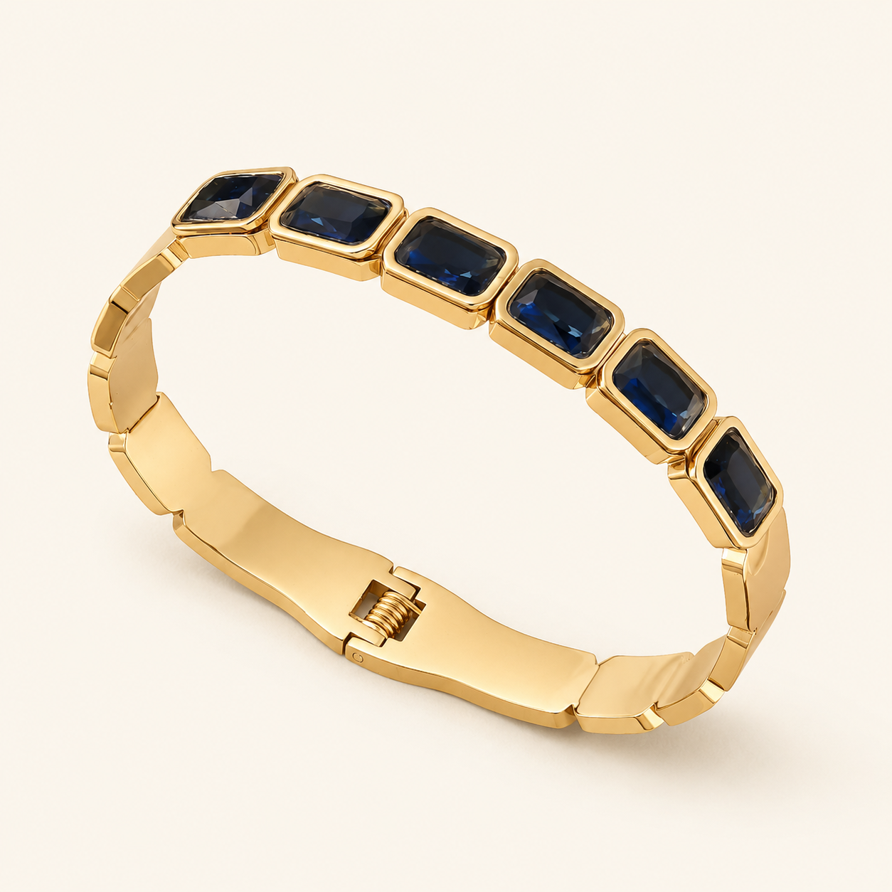 Gold bracelet with blue gemstones on a light beige background